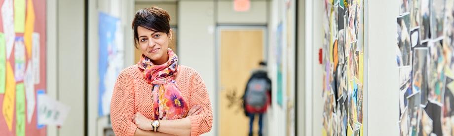 Teacher standing in school hallway with arms crossed