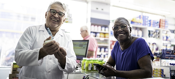 Pharmacist and patient smiling, at counter